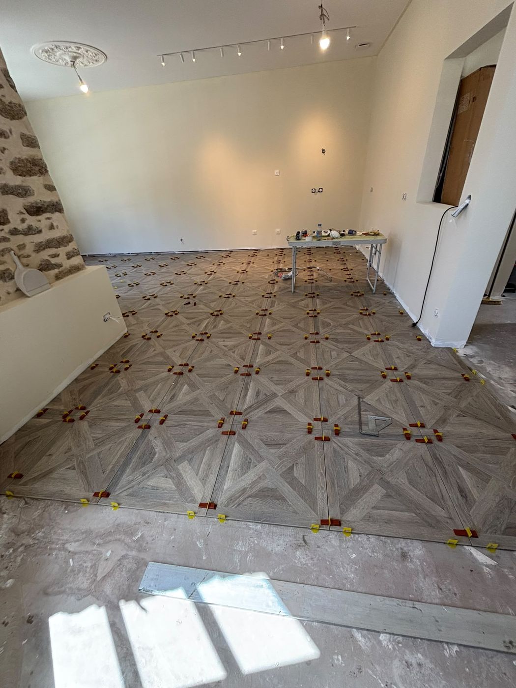 Sol en carrelage imitation parquet posé en motif Versailles, cales de pose encore en place.
