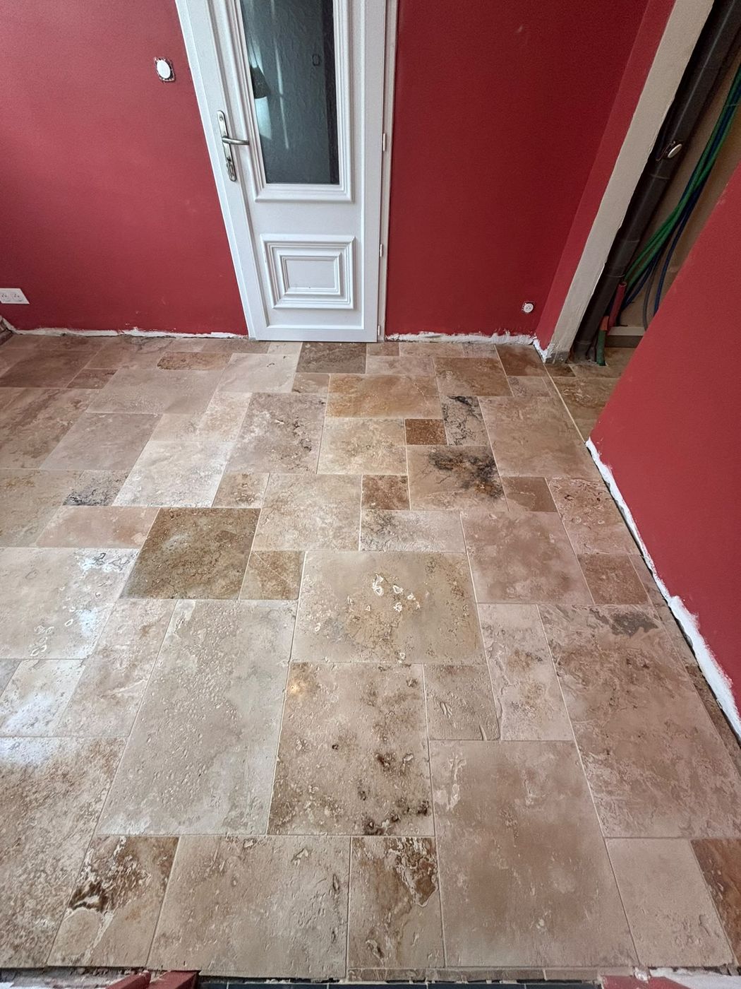 Sol en travertin posé avec plusieurs tailles de carreaux mélangées.