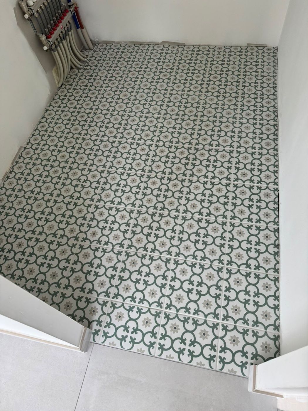 Sol en carreaux de ciment à motif vert et beige, posés bord à bord avec des joints fins.